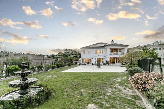 rear view of house featuring a patio area, roof mounted solar panels, a balcony, and a chimney