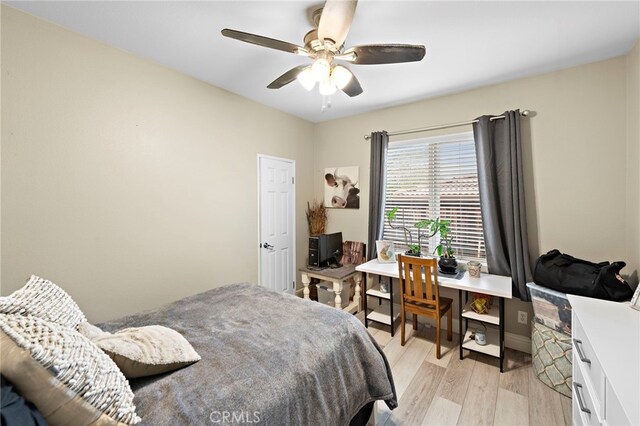 bedroom with light wood-type flooring, a ceiling fan, and baseboards