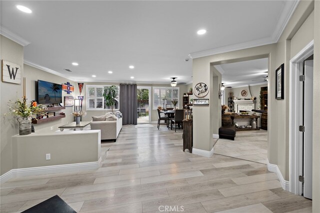 living room with ceiling fan, ornamental molding, recessed lighting, a fireplace, and light wood finished floors