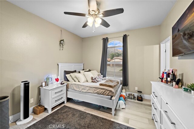 bedroom with light wood-type flooring, baseboards, and a ceiling fan