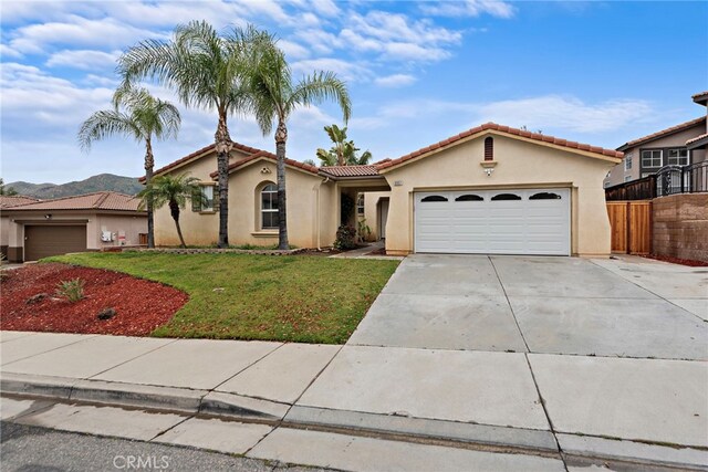 mediterranean / spanish house with stucco siding, a garage, concrete driveway, and a tile roof