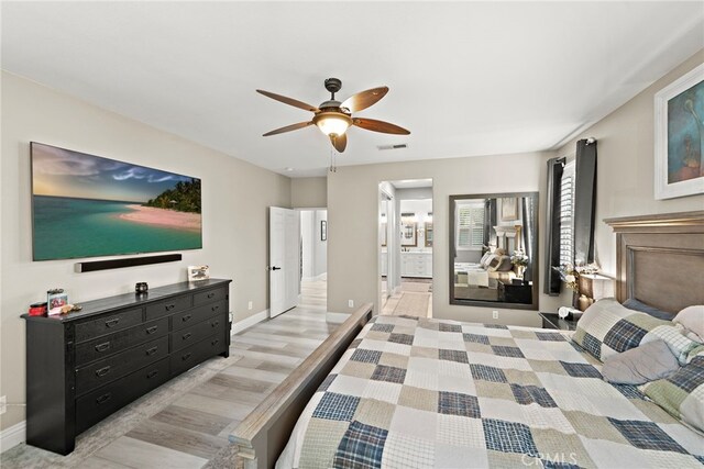 bedroom with baseboards, ensuite bathroom, a ceiling fan, and light wood finished floors