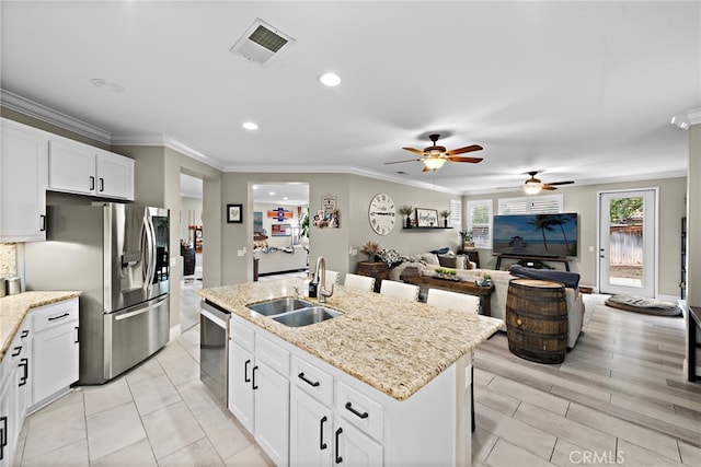 kitchen featuring a sink, appliances with stainless steel finishes, a ceiling fan, a center island with sink, and white cabinets