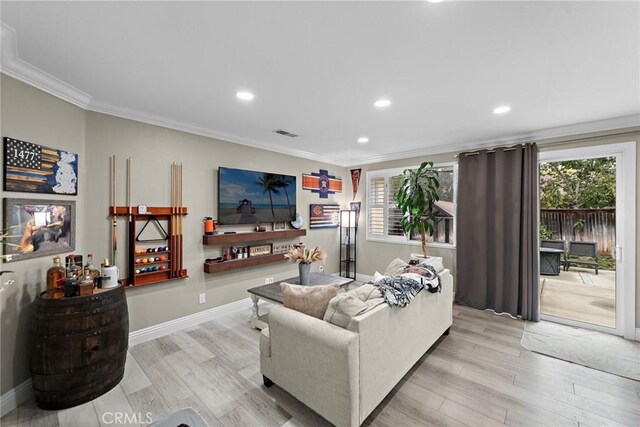 living area with crown molding, wood finished floors, plenty of natural light, recessed lighting, and baseboards