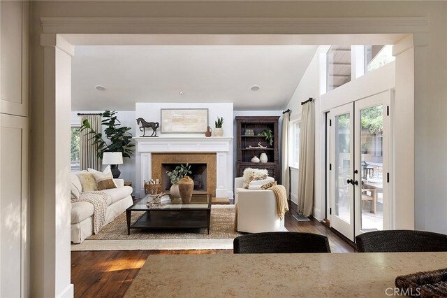 living area featuring wood finished floors, a premium fireplace, vaulted ceiling, and french doors