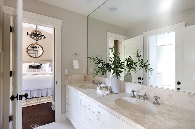 bathroom featuring double vanity, ensuite bathroom, and a chandelier