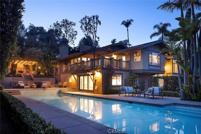 back of property featuring stucco siding, an outdoor pool, a patio, and a chimney