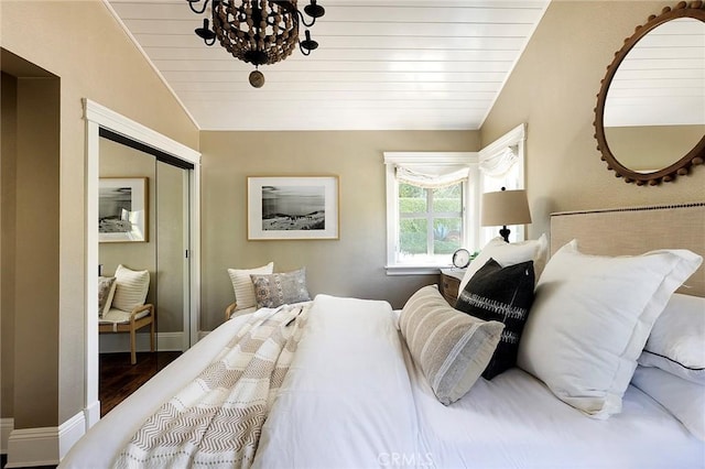 bedroom featuring lofted ceiling, a chandelier, a closet, wood ceiling, and baseboards