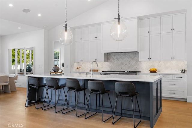 1530 Anita Ln, Newport Beach, CA 92660 - kitchen featuring a large island, backsplash, light wood-style flooring, white cabinets, and lofted ceiling