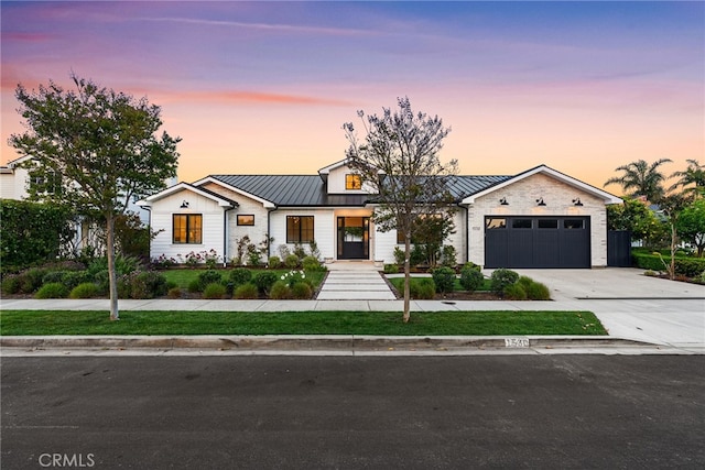 modern farmhouse style home with a standing seam roof, driveway, a garage, and metal roof