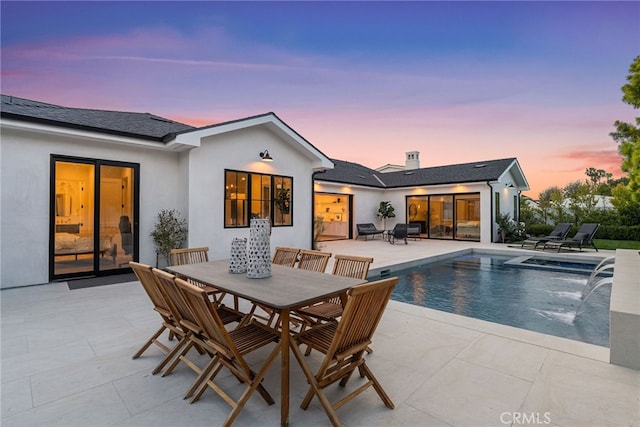 1530 Anita Ln, Newport Beach, CA 92660 - back of house at dusk featuring a patio, an outdoor pool, outdoor dining area, and stucco siding