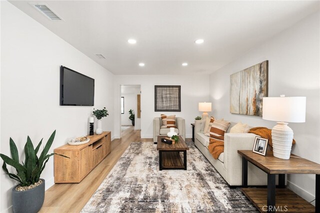 living area with recessed lighting, light wood-style flooring, and baseboards