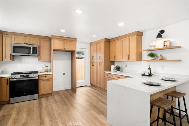 kitchen featuring stainless steel appliances, light countertops, light wood-style flooring, a peninsula, and recessed lighting