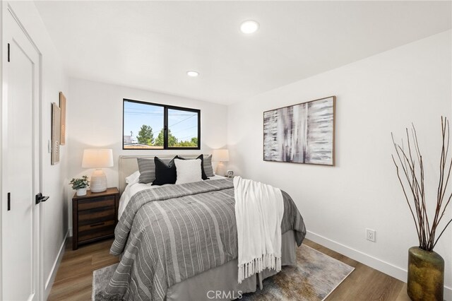 bedroom with baseboards, wood finished floors, and recessed lighting