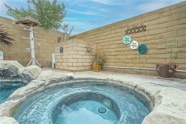 view of swimming pool with an in-ground hot tub and fence