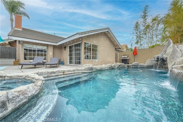 view of swimming pool featuring a patio area, a fenced backyard, and a pool with connected hot tub