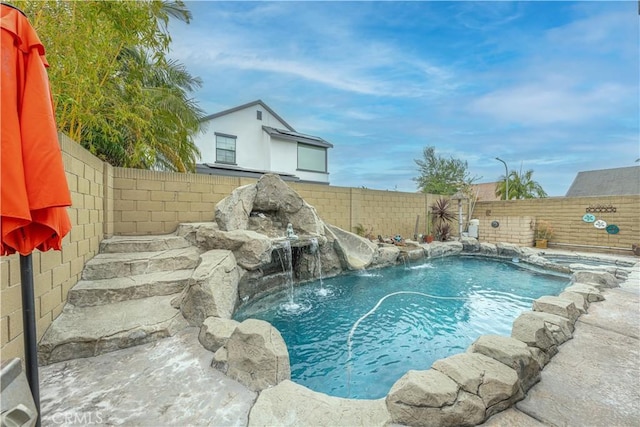 view of swimming pool with a fenced backyard and a pool with connected hot tub