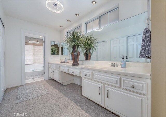 full bathroom with double vanity, a tub to relax in, and recessed lighting