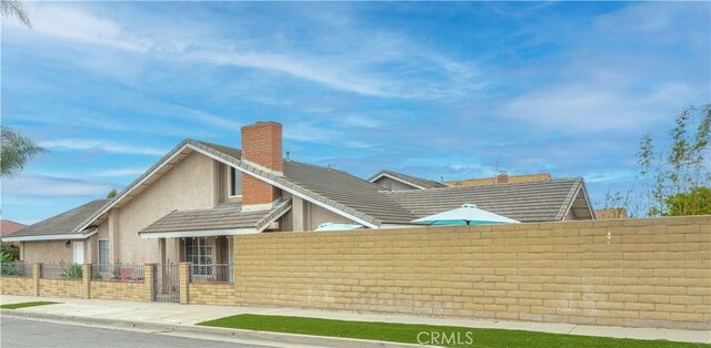 rear view of house with a fenced front yard, a chimney, and stucco siding