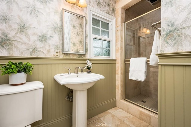 full bathroom with a shower stall, tile patterned floors, toilet, wainscoting, and wallpapered walls