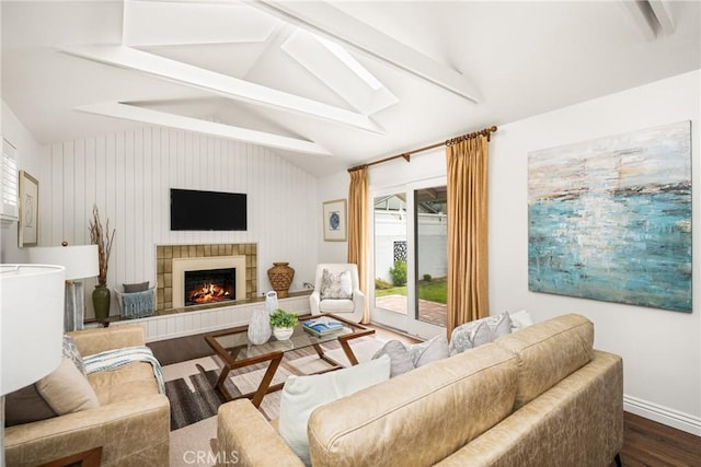 living room with dark wood-style flooring, a tiled fireplace, and baseboards