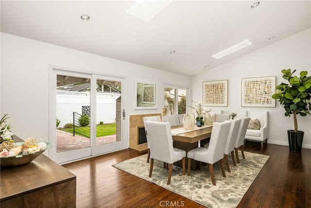 dining space with a skylight, lofted ceiling, dark wood-style floors, recessed lighting, and baseboards