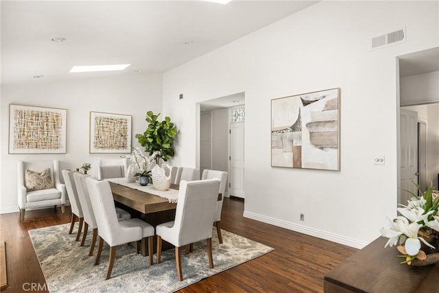 dining space featuring vaulted ceiling, wood finished floors, baseboards, and a skylight
