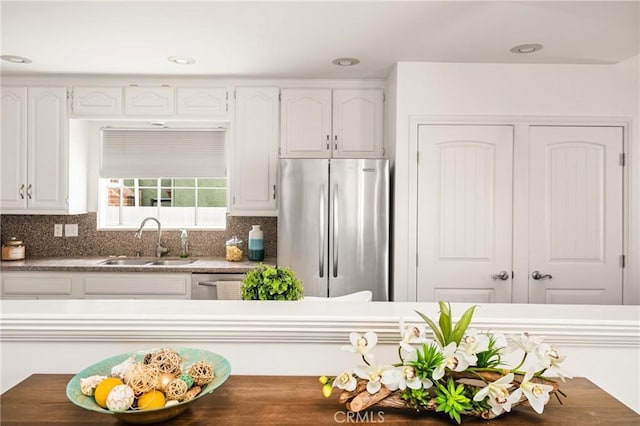 kitchen with freestanding refrigerator, a sink, white cabinets, tasteful backsplash, and recessed lighting