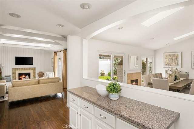 kitchen featuring a warm lit fireplace, dark wood-type flooring, white cabinetry, open floor plan, and recessed lighting