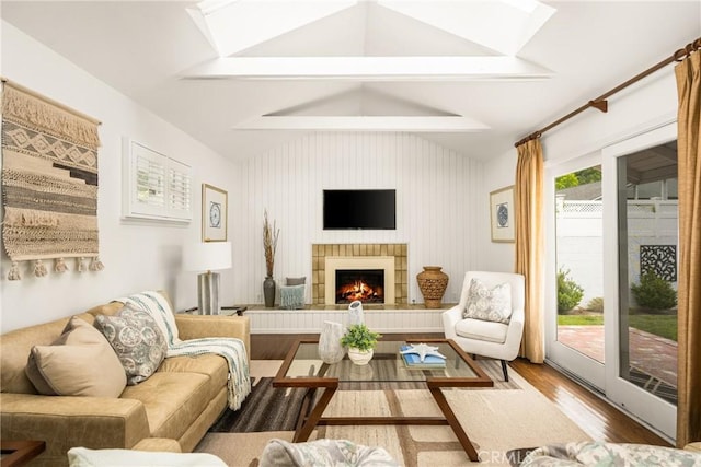 living area featuring wood finished floors, a tile fireplace, and a skylight
