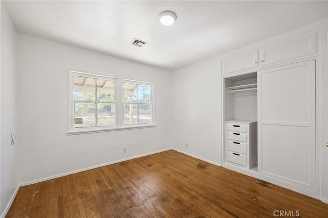 unfurnished bedroom featuring wood finished floors, baseboards, and a closet