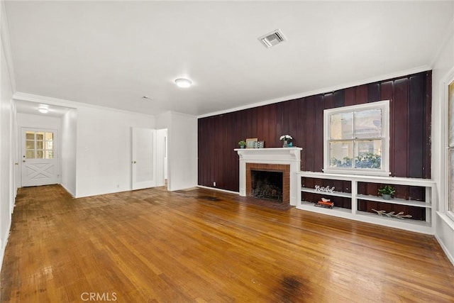 unfurnished living room with crown molding, wood finished floors, and a fireplace