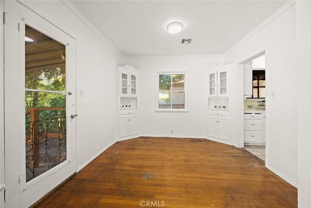 entryway with plenty of natural light, wood finished floors, crown molding, and baseboards