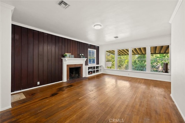 unfurnished living room featuring hardwood / wood-style floors, crown molding, a fireplace, and baseboards