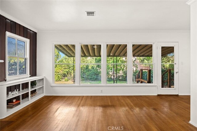 spare room featuring wood finished floors, baseboards, and crown molding