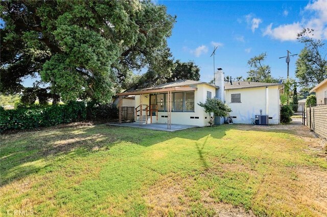 back of property with central AC, stucco siding, a patio, and a chimney