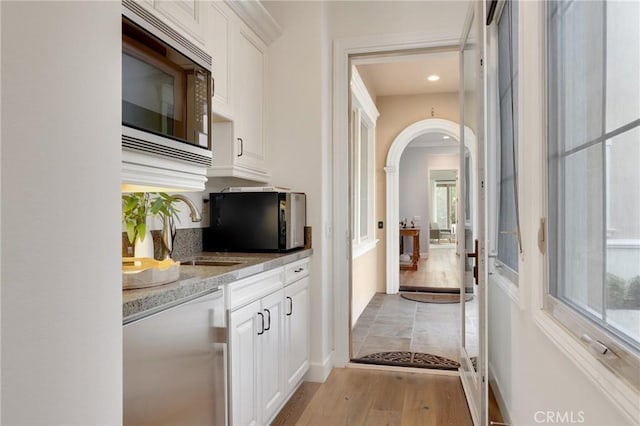 25 Tenderfoot, Irvine, CA 92602 - bar area with stainless steel microwave, dishwasher, arched walkways, light wood-type flooring, and a sink