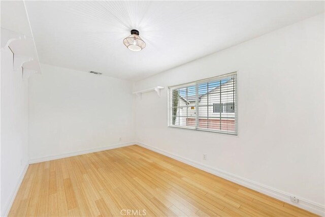 spare room featuring light wood-style floors and baseboards