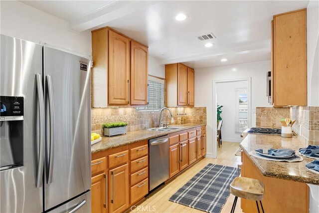 kitchen featuring appliances with stainless steel finishes, a sink, healthy amount of natural light, backsplash, and recessed lighting