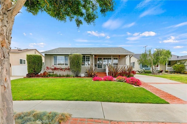 ranch-style house featuring covered porch, a front yard, and stucco siding