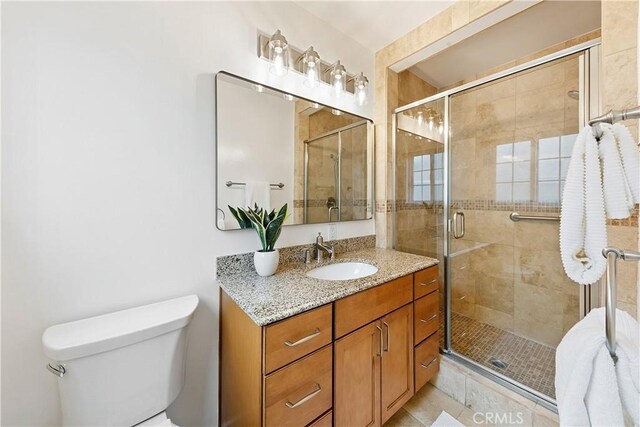 full bathroom with a stall shower, vanity, and toilet