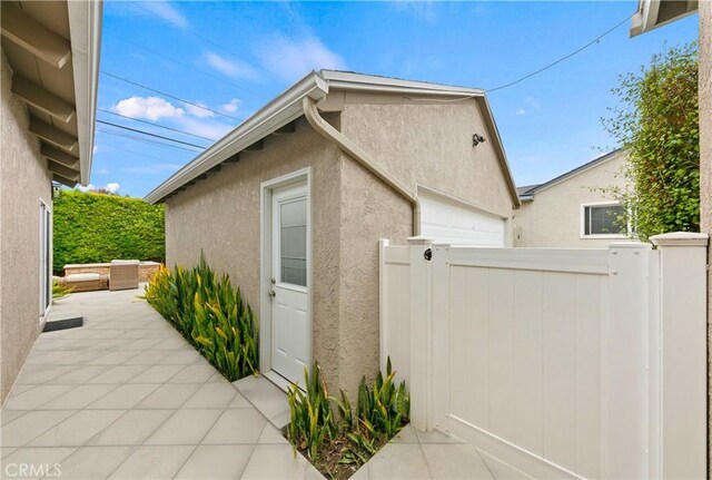 view of side of property with stucco siding, fence, an outdoor structure, and a garage