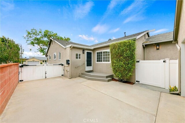 back of house featuring a gate, a patio, stucco siding, and fence