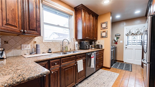 kitchen featuring stainless steel appliances, a sink, light wood-style floors, decorative backsplash, and recessed lighting