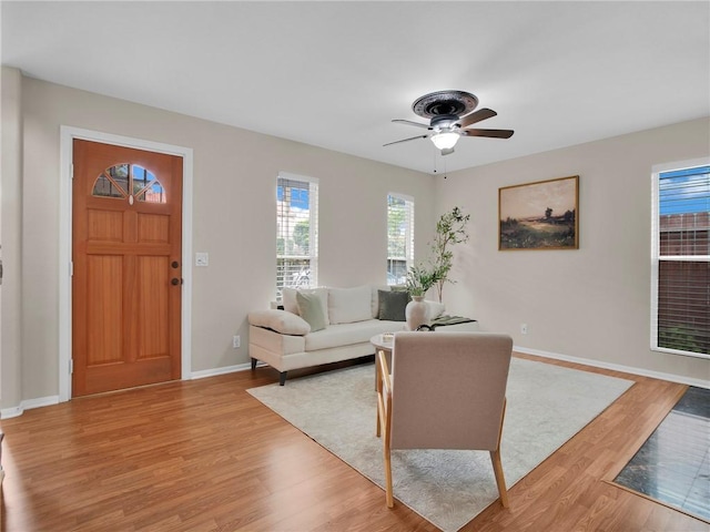 living area with light wood-style flooring, baseboards, and ceiling fan
