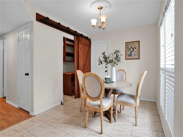 dining space featuring a barn door, a chandelier, and baseboards
