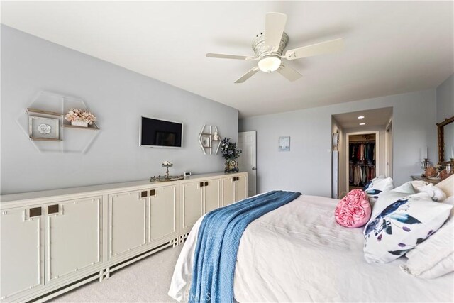 bedroom with ceiling fan, light colored carpet, and a spacious closet
