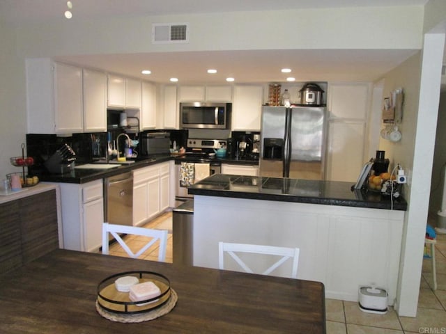 2640 Luciernaga St, Carlsbad, CA 92009 - kitchen with appliances with stainless steel finishes, a peninsula, dark countertops, and white cabinetry