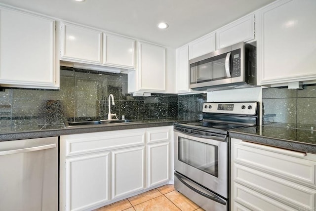 2640 Luciernaga St, Carlsbad, CA 92009 - kitchen featuring appliances with stainless steel finishes, white cabinets, dark countertops, light tile patterned floors, and backsplash