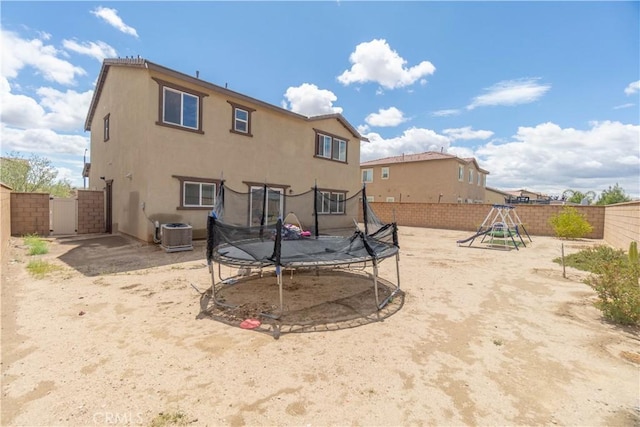 11952 Saxton Way, Victorville, CA 92392 - rear view of house featuring a trampoline, a fenced backyard, a playground, a gate, and stucco siding